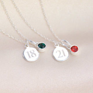 Silver landmark birthstone necklace shown close up with emerald and ruby birthstone charms