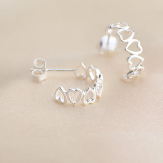 Silver open heart hoop earrings shown close up 