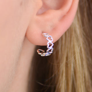 Silver open heart hoop earrings shown close up on model