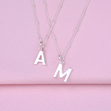 Close up detail of modern initial letter charm necklaces shown close up