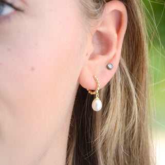Gold beaded hoop earrings with pearl drops shown close  up on model