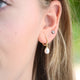 Gold beaded hoop earrings with pearl drops shown close  up on model