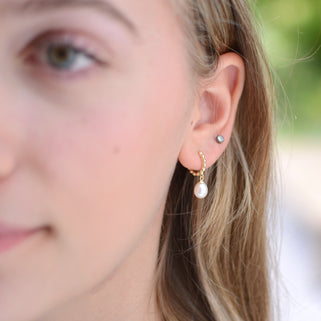 Gold beaded hoop earrings with pearl drops shown close  up on model
