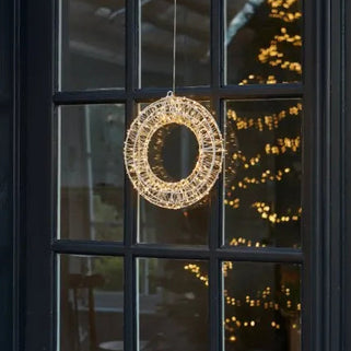 Decorative wreath light hanging on a glass door with a blurred indoor background