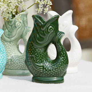 Three ceramic vases with fish designs on a white surface.