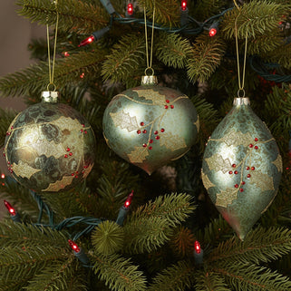 Three round Holly Berry Glass Baubles with green and red glitter, hanging from gold strings.