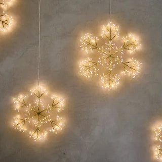 Decorative string lights shaped like snowflakes on a textured wall.