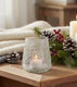 Cozy indoor setting with candles, pinecones, and a blanket on a wooden surface.