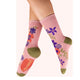 Pink socks with floral designs worn by a person on a white background