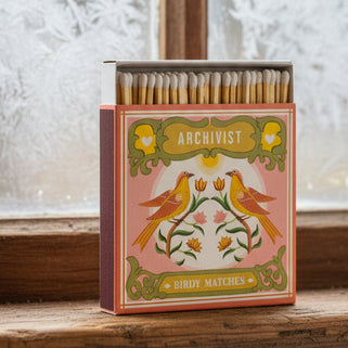 Matchbox with decorative design on a wooden surface near a window with frosty glass.