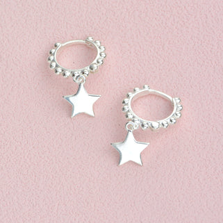 Sterling Silver beaded hoop star charm huggies shown close up .