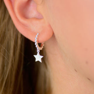 Sterling Silver beaded hoop star charm huggies shown close up on model.