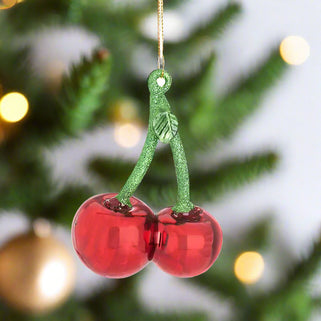 Decorative ornament shaped like two red cherries with green stems on a white background