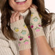 Woman wearing a beige sweater and embroidered fingerless gloves on a white background
