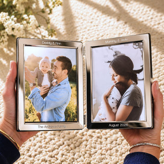 Two hands holding a silver photo frame with family photos on a textured surface.