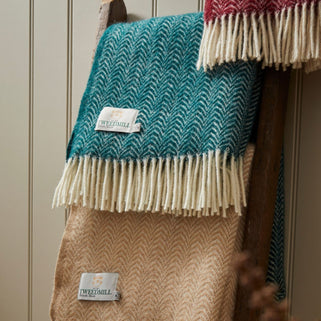 emerald green and green wool throw blanket shown in shot with other colours drapes on wooden ladder.