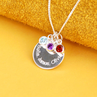 Personalised Family Names Birthstone Necklace - Silver engraved circle disc with "Bella, James, Olivia" and three birthstones  March/Aquamarine, July/Ruby, February/Amethyst shown close up
