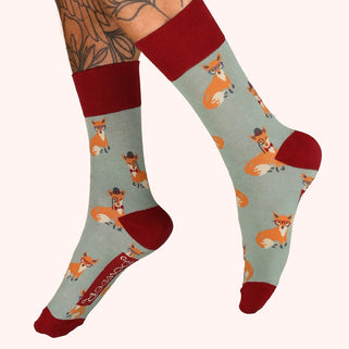 Socks with fox pattern worn by a person with tattoos on a white background