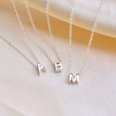 Girls slider inital necklace  shown close up with letters A, B and M on a fine silver chain