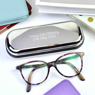 Chrome Glasses Case with Personalised Message "Happy 23rd Birthday 24th May 2023" engraved in straight walk font, shown in close up shot on desk with glasses 