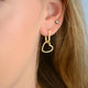 Gold Heart Shape Drop Hoop Earrings shown close up on model