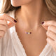 Necklace with colorful gemstones held by a person wearing a white top.