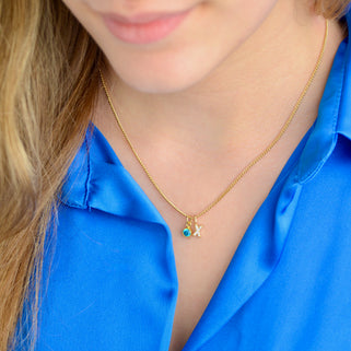 Gold Sparkle Kiss necklace with blue topaz birthstone shown close up on model