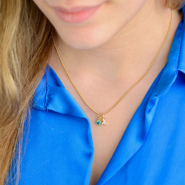 Gold Sparkle Kiss necklace with blue topaz birthstone shown close up on model
