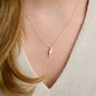 Gold plated sterling silver lightning bolt necklace shown in close up shot on model.
