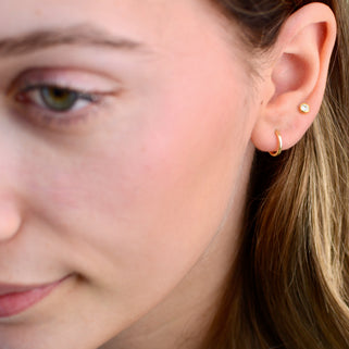 Simple Gold Sleeper Huggie Hoop Earrings shown close up on model