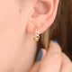 Gold open heart hoop earrings shown close up on model