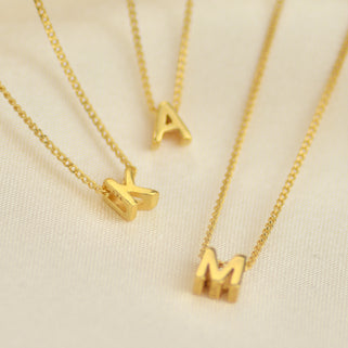 Personalised Gold Mini Slider Initial Charm Necklace shown close up. Letter A, K and M