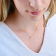 Personalised Gold Mini Slider Initial Charm Necklace letter M shown close up on model.