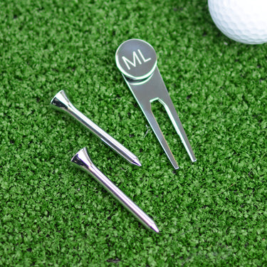 Golf Ball marker and tee set shown close up with engraving on ball marker