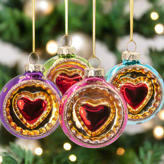 Colorful heart-shaped Christmas ornaments hanging against a white background