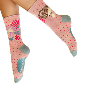 Pink socks with hedgehog design worn by a person on a white background