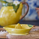 Yellow ceramic lemon squeezer on a wooden surface with a blurred background
