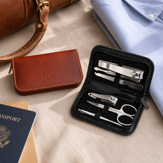 Manicure set in a black case with a brown leather wallet and blue shirt on a beige surface.