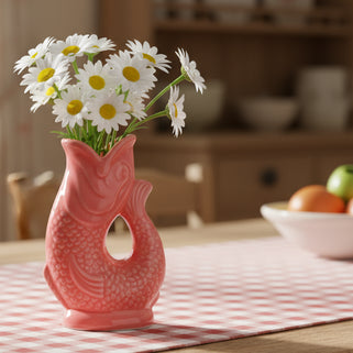 Coral-colored ceramic fish-shaped object on a white background