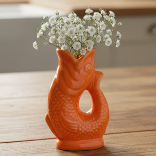 Orange ceramic fish-shaped vase on a white background