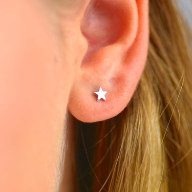 Sterling Silver Plain Minin star studs earrings shown close up on model.