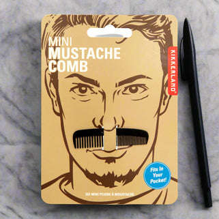 Package of a mini mustache comb with a man's face illustration on a beige background.