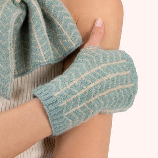 Woman wearing a matching teal knit hat, scarf, and gloves on a white background