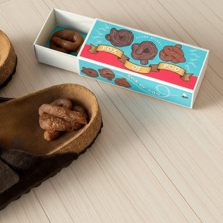 Box of 'Poo' with brown objects on a textured surface, featuring 'Gift of the Year' finalist label.