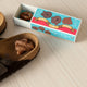 Box of 'Poo' with brown objects on a textured surface, featuring 'Gift of the Year' finalist label.