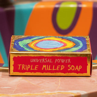 A colorful bar of Universal Power Soap packaging with artistic designs and the product name visible.
