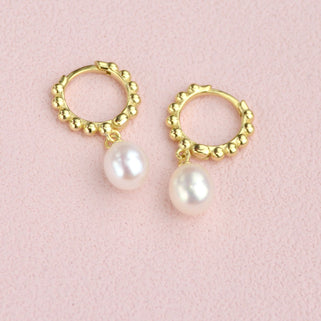 Gold beaded hoop earrings with pearl drops shown close  up 