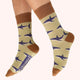 Beige socks with shark pattern and brown accents worn by a person on a white background