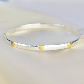 Sterling Silver Mia Hearts Bangle shown close up with brass heart detailing