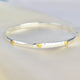 Sterling Silver Mia Hearts Bangle shown close up with brass heart detailing